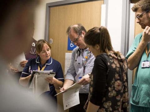A doctor and a Matron check patient information in a team meeting