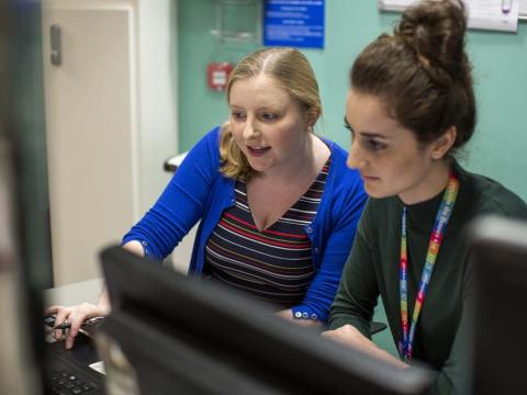 Two doctors check information together on a computer screen