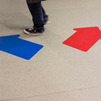 A person walks over two arrows on the floor. 